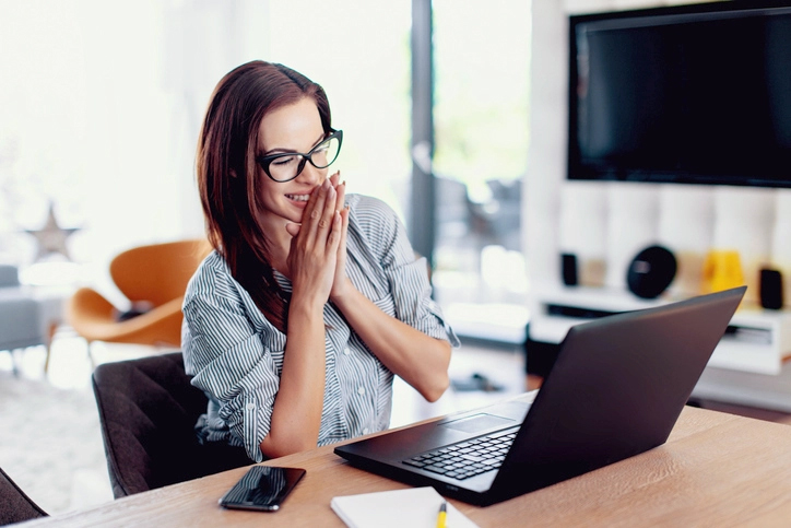 Woman sitting at laptop smiling because she is applying for a grant for her small business