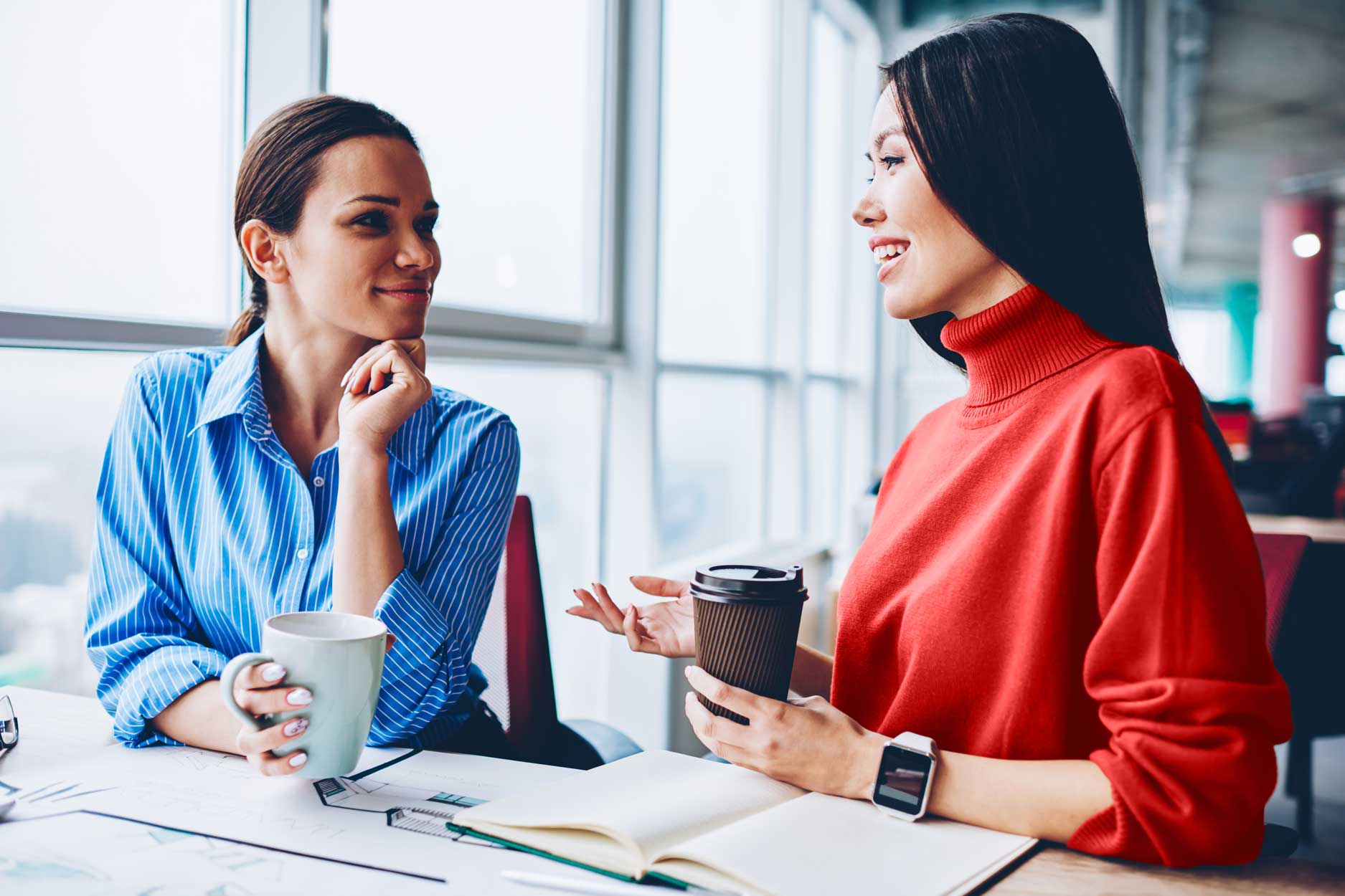 Two females conversing over coffee.
