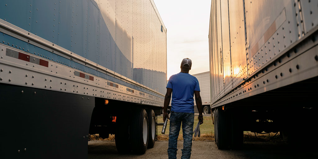 Truck driver walking between two trucks with the sun setting.