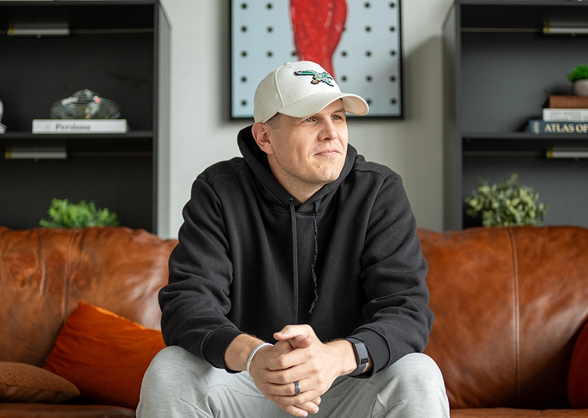 James Carbary of Sweet Fish sitting on brown leather couch in living room