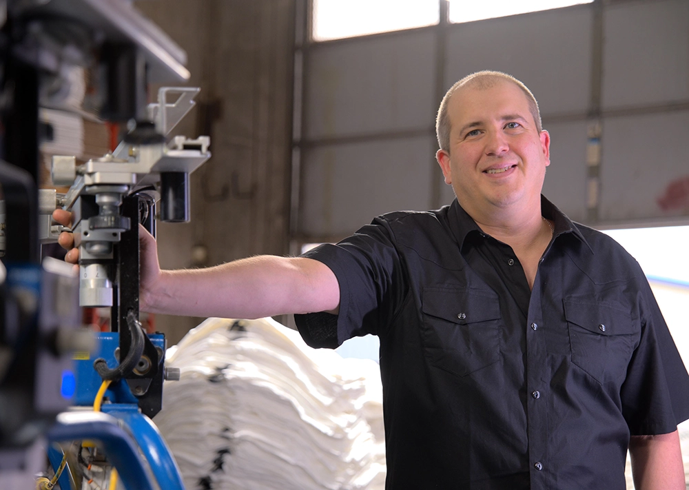 Artis Proof Collective, owner posing with screen printing machinery